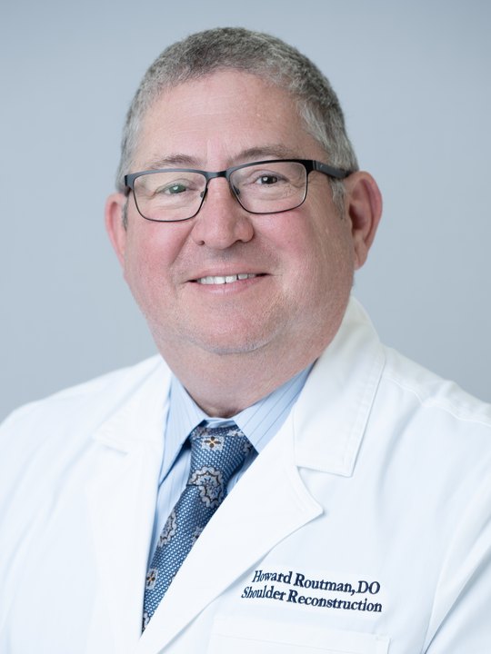 Dr. Howard Routman, wearing a white coat embroidered Howard Routman, DO — Shoulder Reconstruction.
