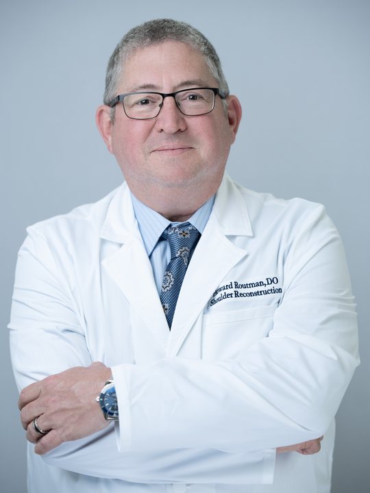 Dr. Howard Routman, wearing a white coat embroidered Shoulder Reconstruction.